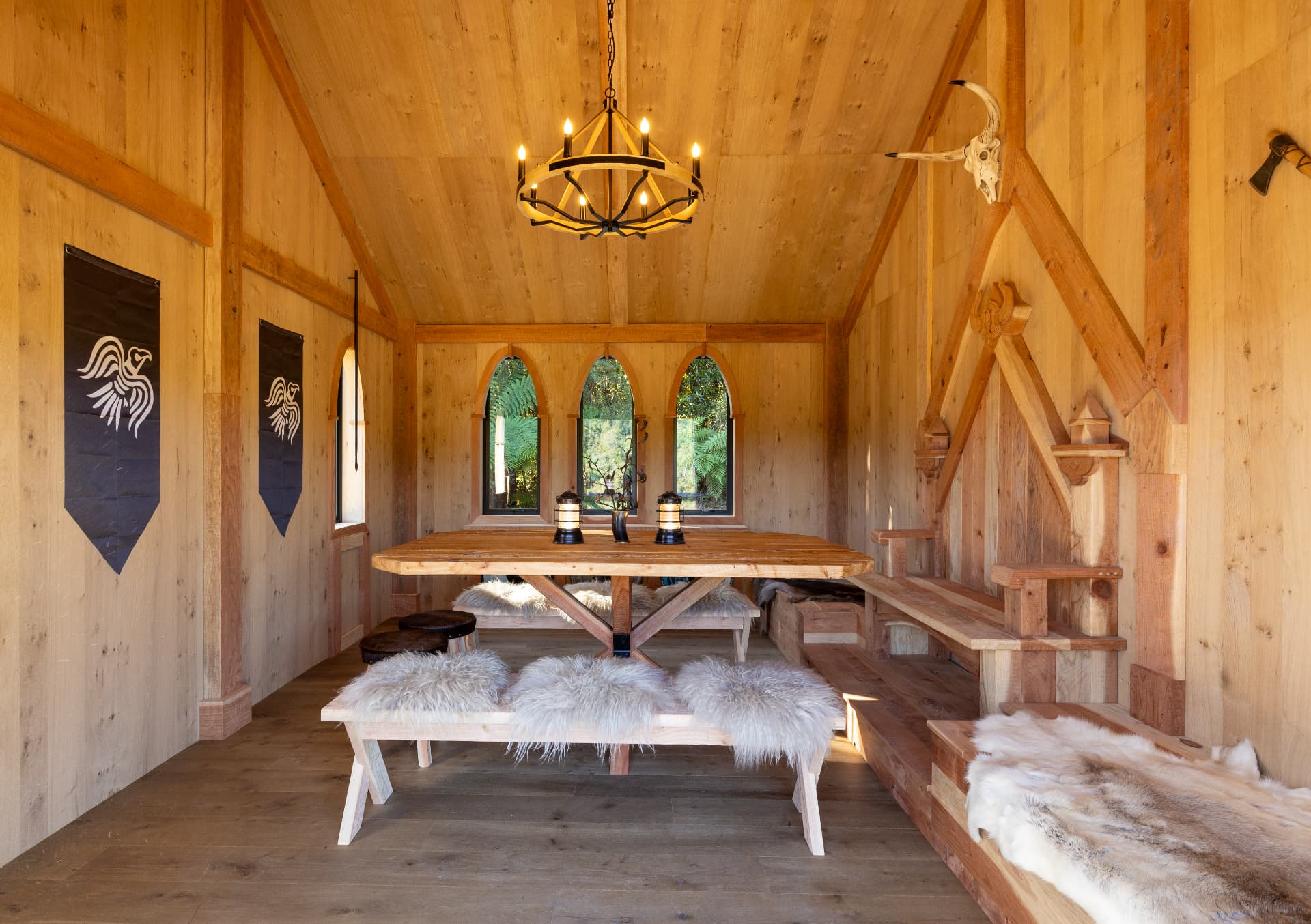 Timber great hall with a long communal table, candles and an open fire